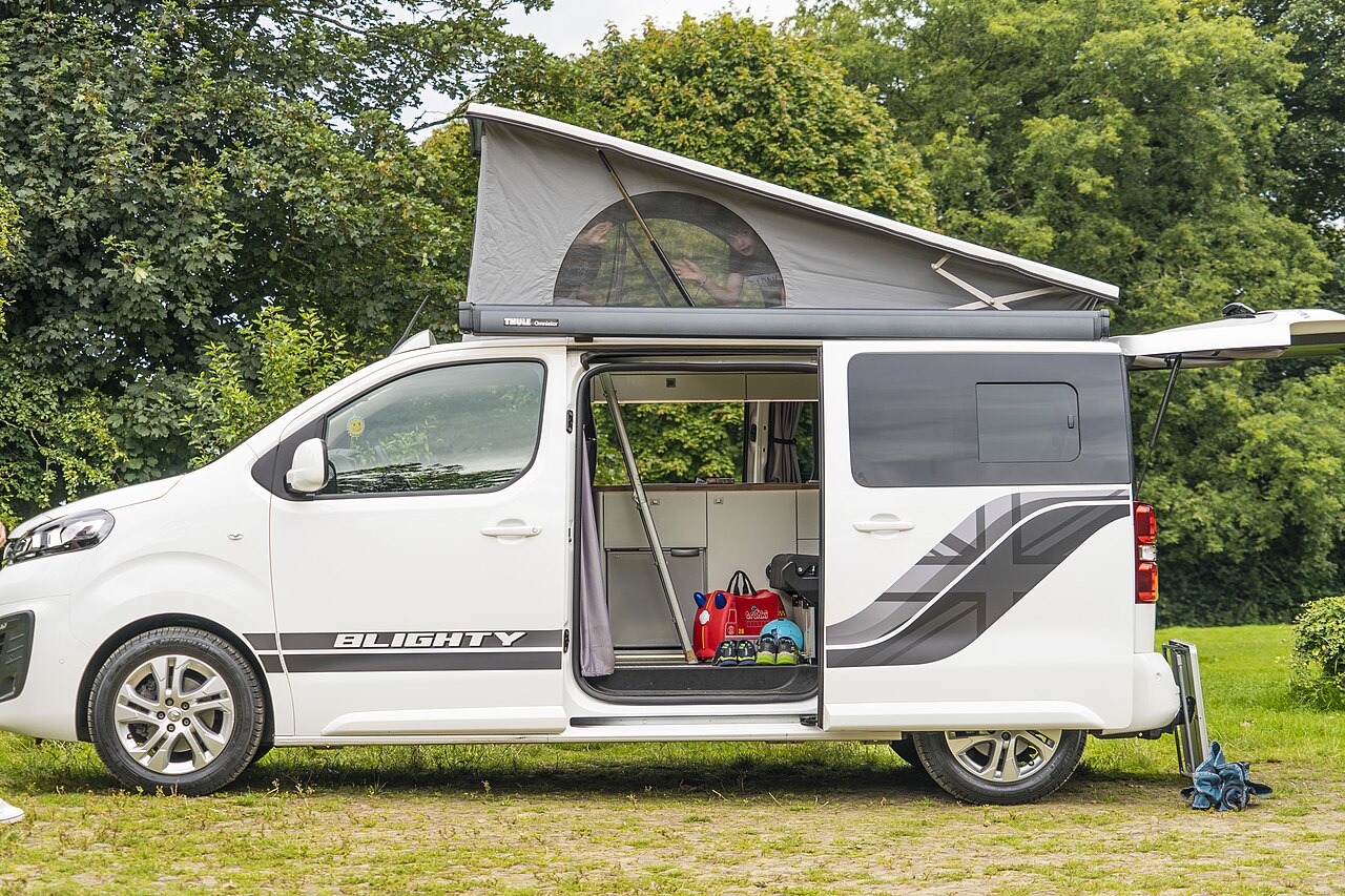 White campervan with open side doors parked on green grass